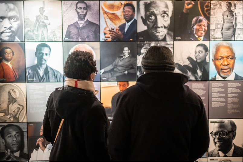 A man and woman look at a series of portraits on the "Black Achievers Wall" at the International Slavery Museum, Liverpool