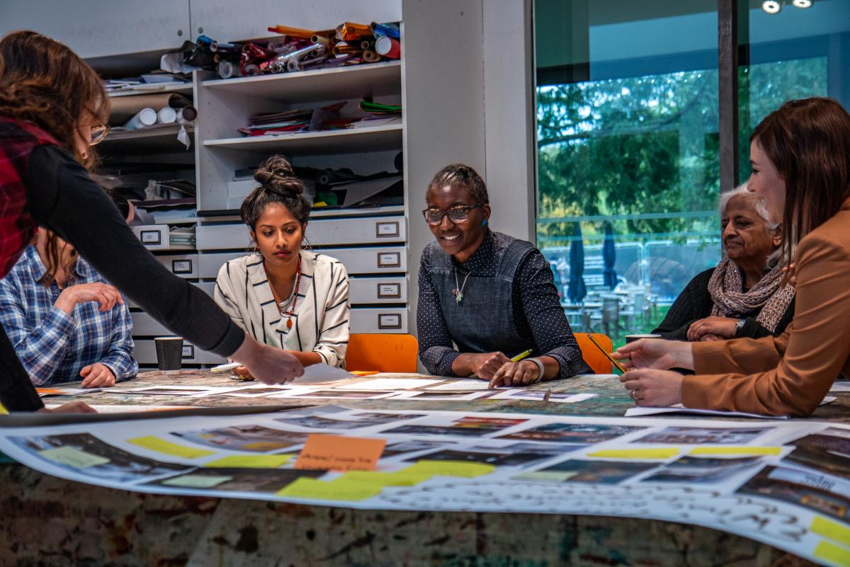 A group of women discuss images laid out on a table