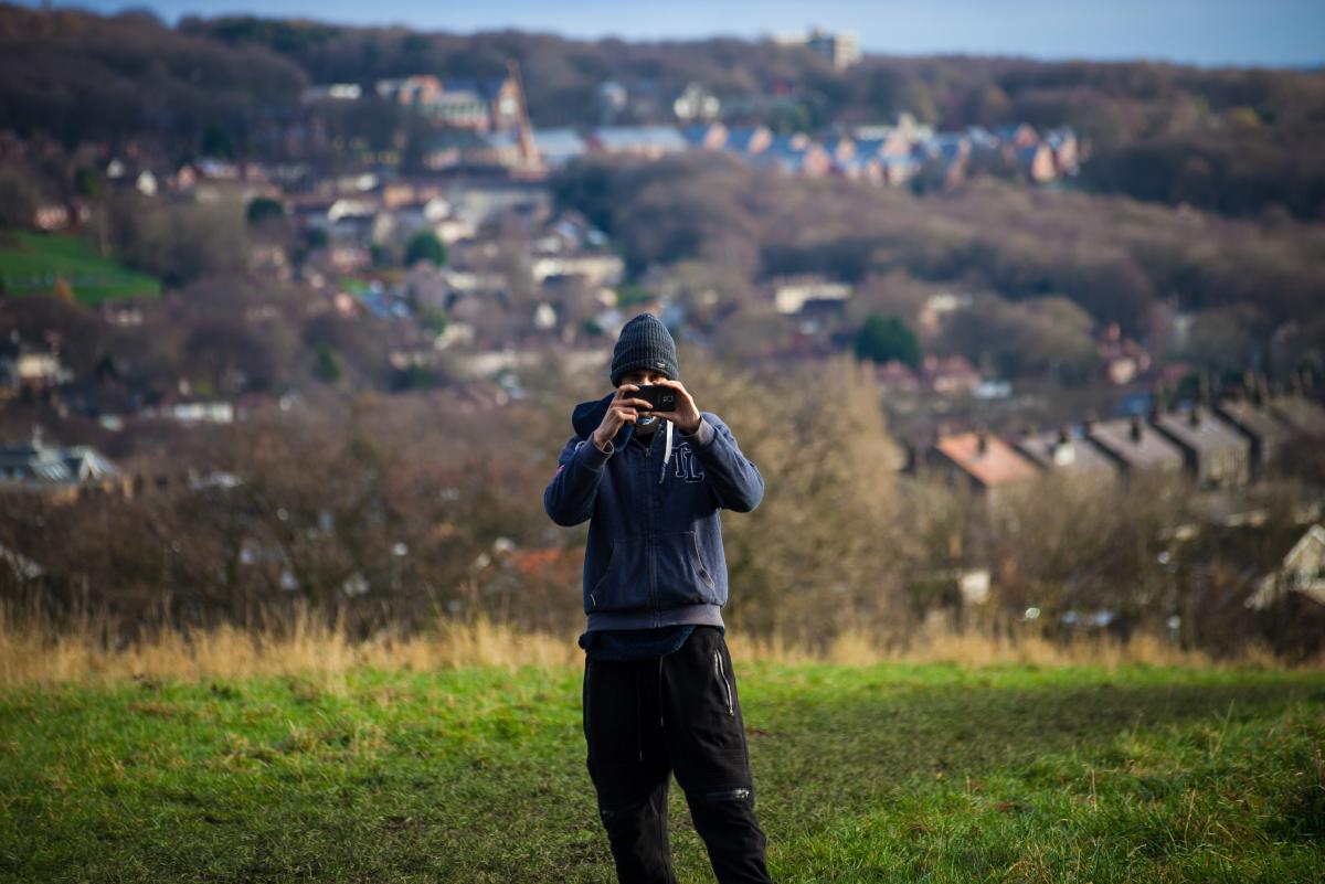 Man About Town participant taking a photo with his phone with Leeds backdrop