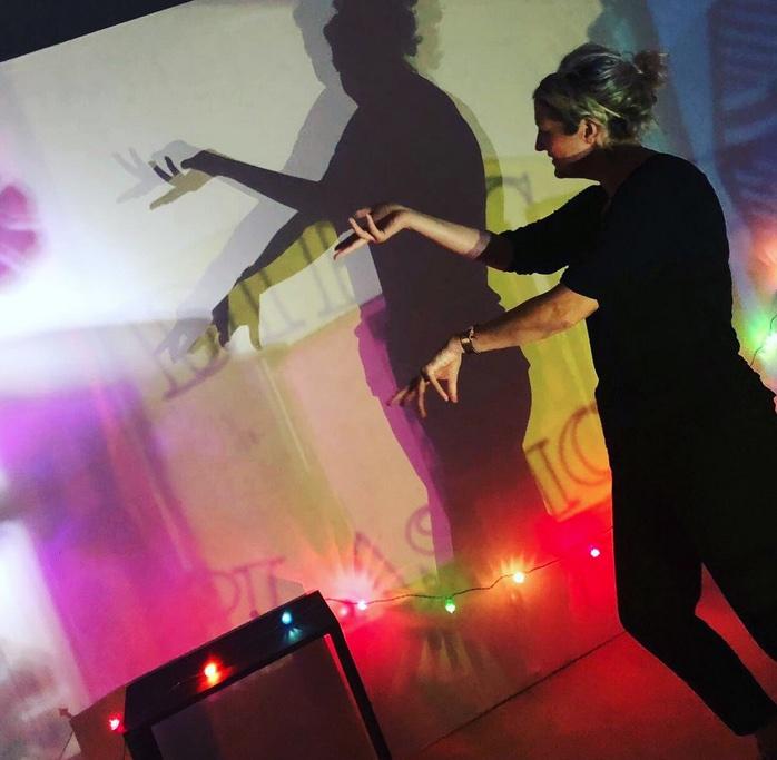 Woman creating shadow shapes on a wall with her hands