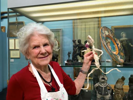 A woman holds a small figure she has made in response to the Beaney's collections