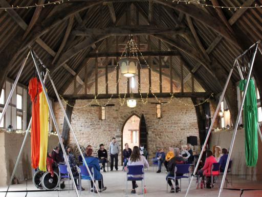 Group creative circus session in a old barn building with colourful flags