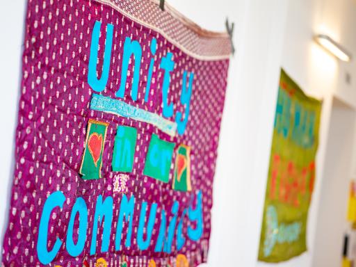 A pink banner with blue writing reading 'Unity and Community'