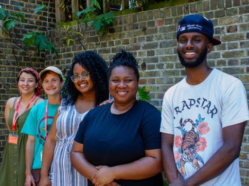 a group of black and white people smiling at the camera against a brick wall